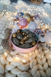 Photo of Beautiful Christmas tree baubles, toys and fairy lights on white knitted fabric