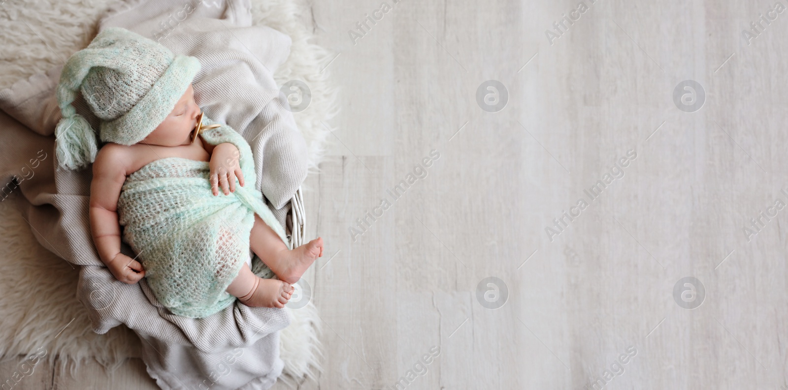 Image of Cute newborn baby sleeping on plaid in basket, top view with space for text. Banner design