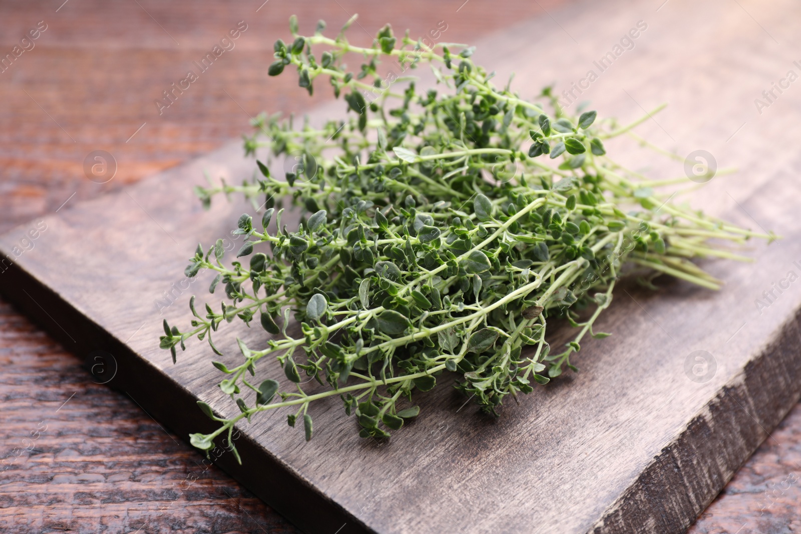 Photo of Bunch of aromatic thyme on wooden table, closeup. Fresh herb