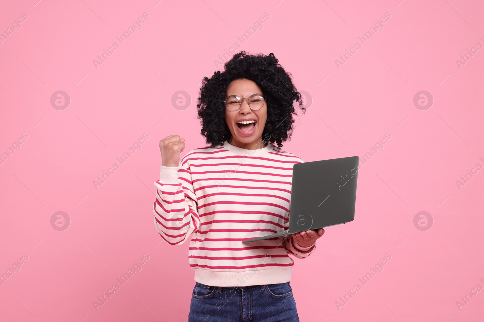 Photo of Emotional young woman with laptop on pink background