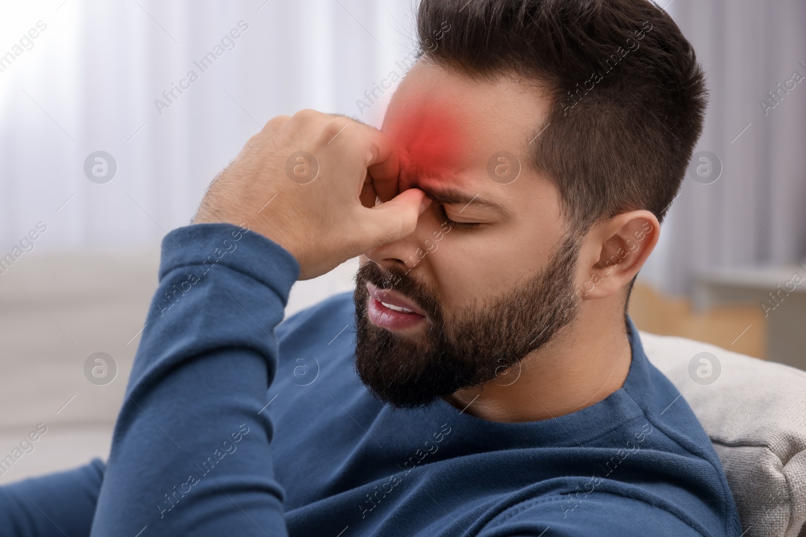 Image of Young man suffering from headache at home