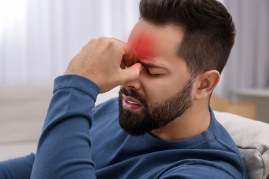 Image of Young man suffering from headache at home