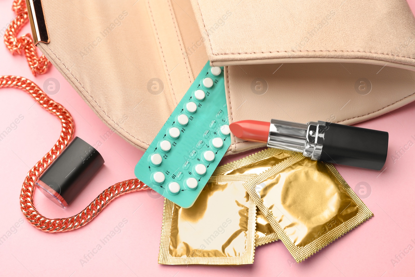 Photo of Purse with condoms and birth control pills on pink background. Safe sex