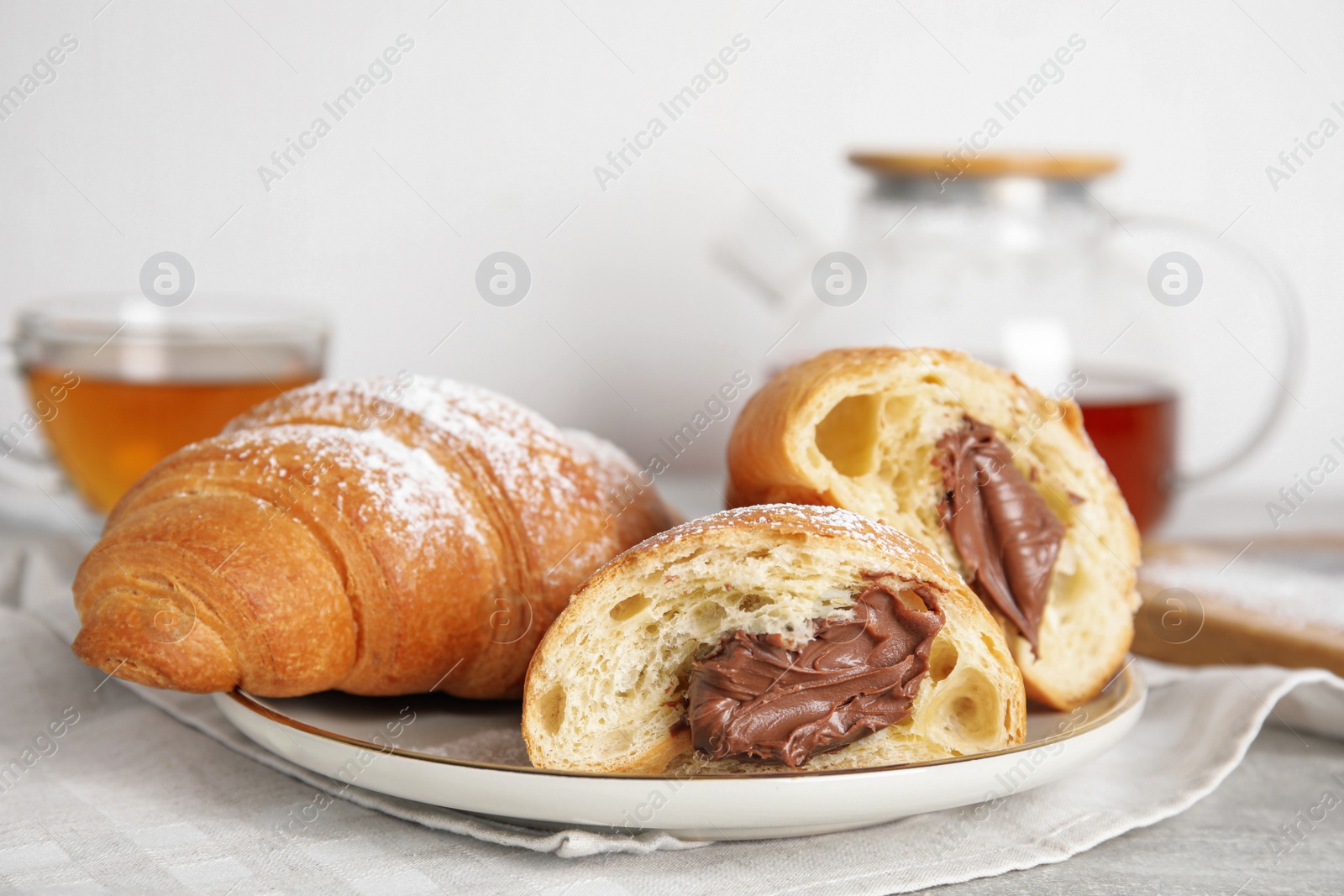 Photo of Tasty croissants with chocolate and sugar powder on table, closeup. Space for text