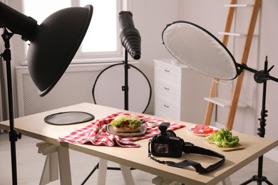 Photo of Professional camera and composition with tasty sandwich on table in photo studio. Food photography