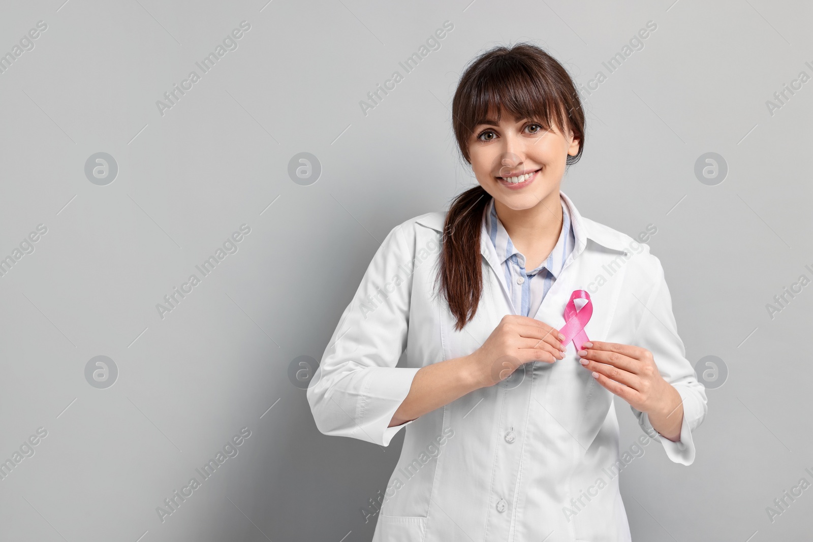 Photo of Mammologist with pink ribbon on light grey background, space for text. Breast cancer awareness