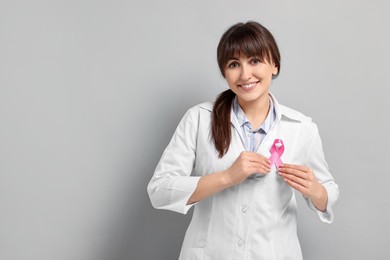 Mammologist with pink ribbon on light grey background, space for text. Breast cancer awareness