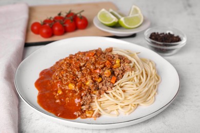 Tasty dish with fried minced meat, spaghetti, carrot and corn served on white textured table