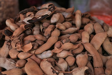 Photo of Heap of delicious tamarinds on counter at market, closeup