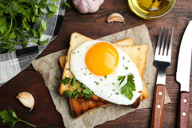 Photo of Tasty fried egg with toasts and parsley on wooden table, flat lay