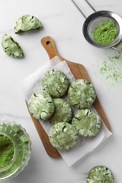 Board with tasty matcha cookies and powder on white marble table, flat lay