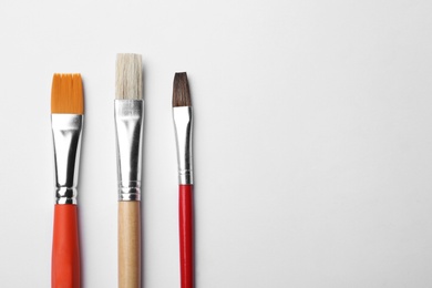 Photo of Different paint brushes on white background, top view. Space for text