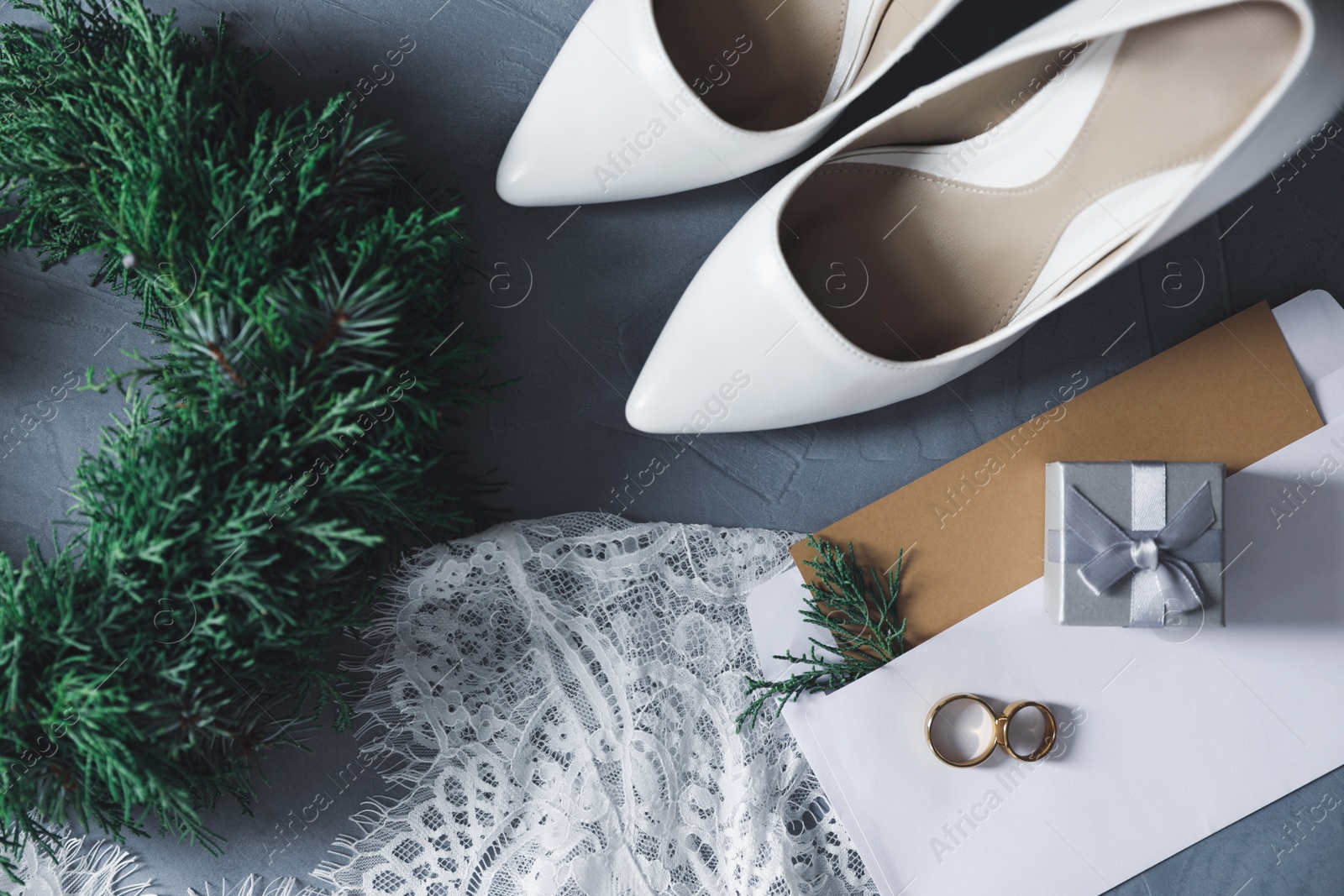 Photo of Flat lay composition with wedding dress, white high heel shoes and rings on grey background