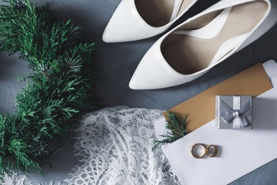 Flat lay composition with wedding dress, white high heel shoes and rings on grey background