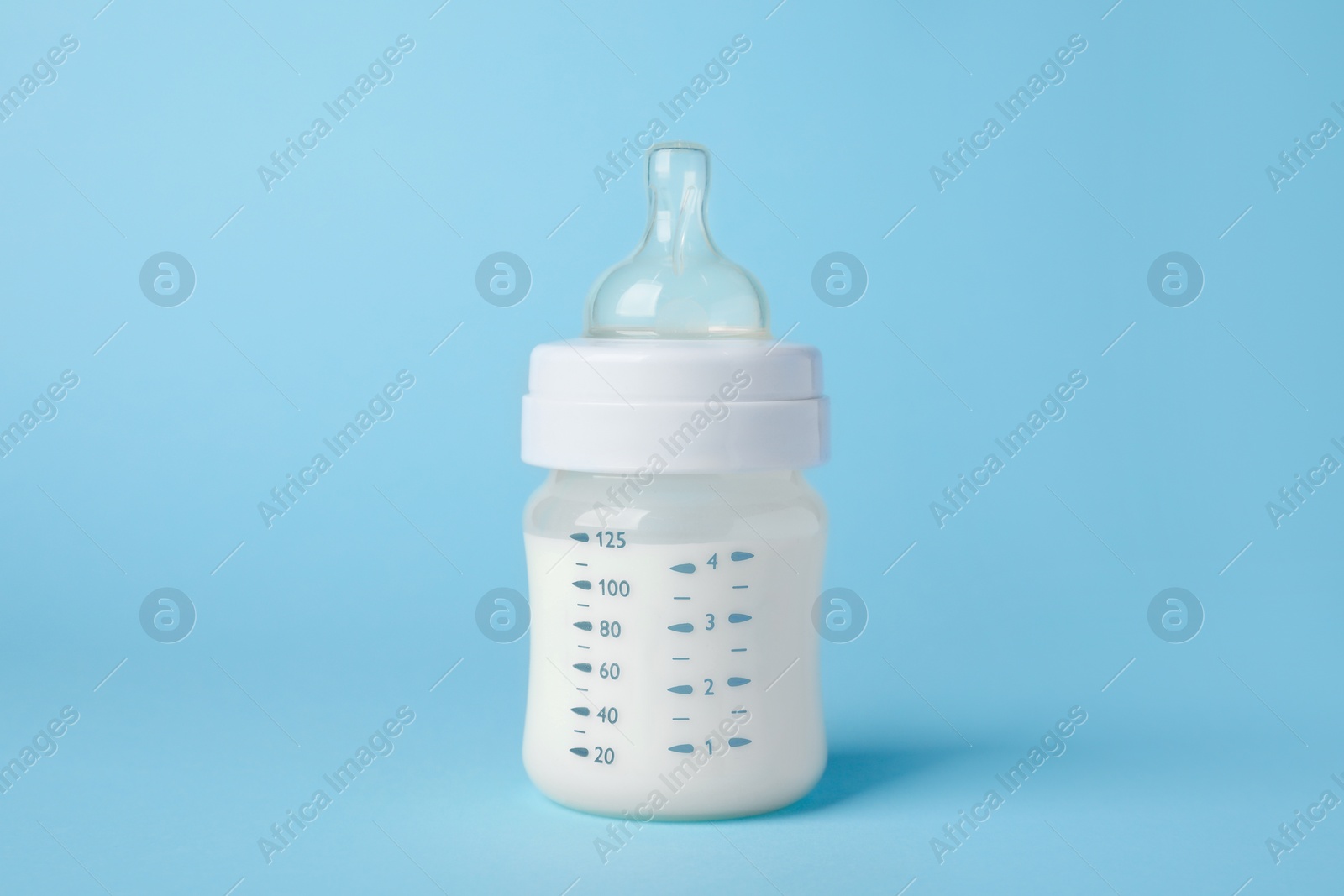 Photo of One feeding bottle with milk on light blue background
