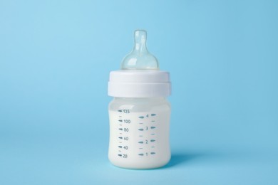 Photo of One feeding bottle with milk on light blue background