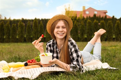 Happy girl having picnic on green grass in park