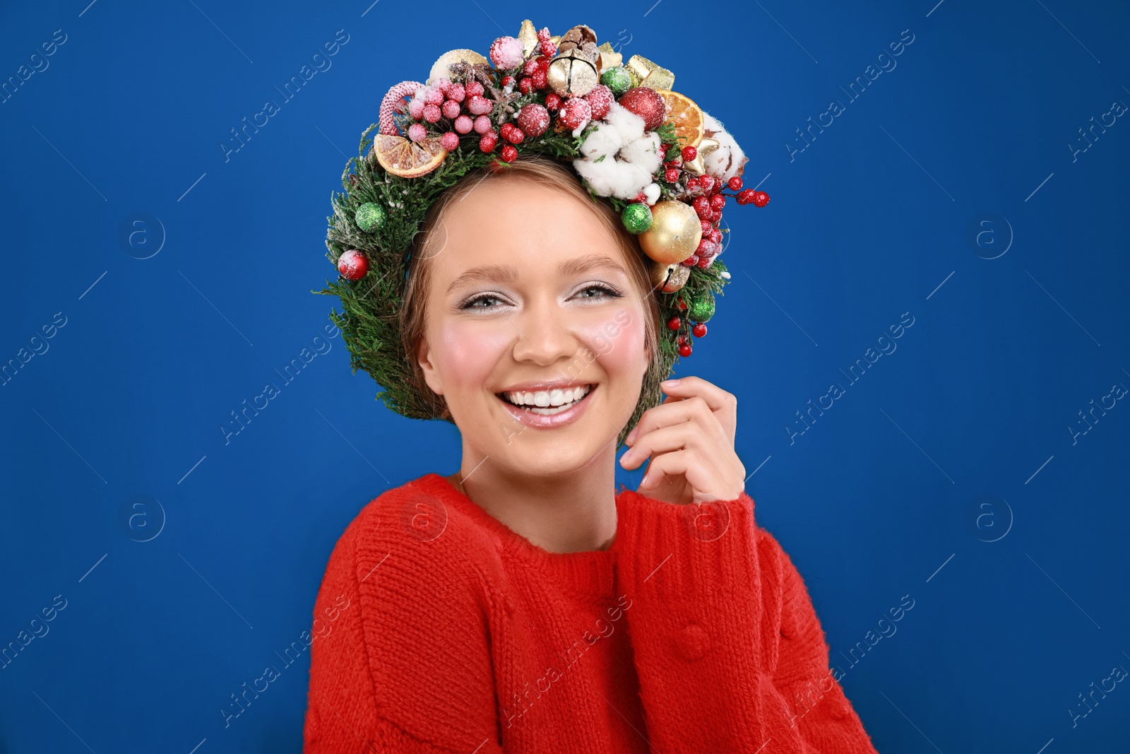 Photo of Beautiful young woman wearing Christmas wreath on blue background