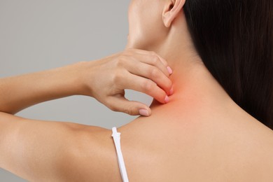 Photo of Suffering from allergy. Young woman scratching her neck on light grey background, back view