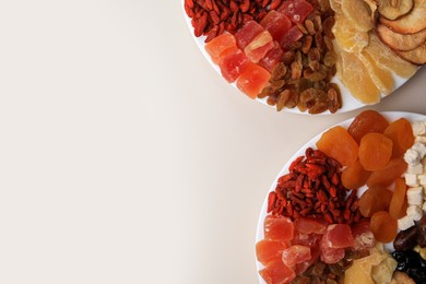 Plates with different dried fruits on white background, top view. Space for text