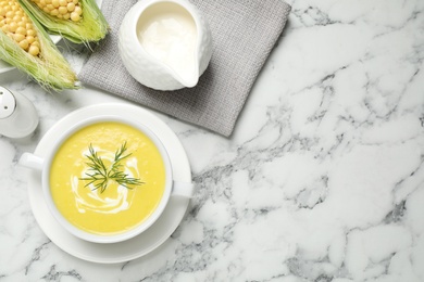 Photo of Delicious creamy corn soup served on white marble table, flat lay. Space for text