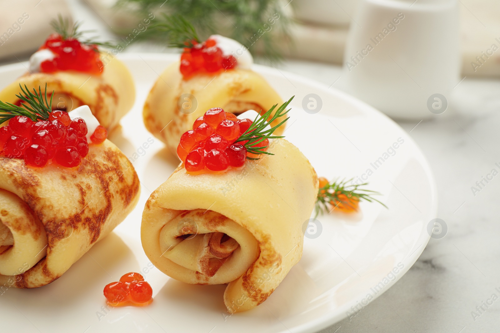 Photo of Delicious thin pancakes with red caviar on plate, closeup