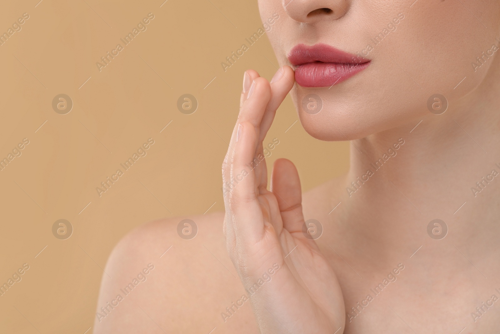 Photo of Young woman with beautiful full lips on beige background, closeup