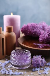 Cosmetic products and lilac flowers on wooden table, closeup