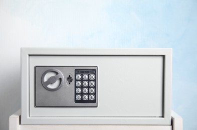 Photo of Closed steel safe on white table against light blue background