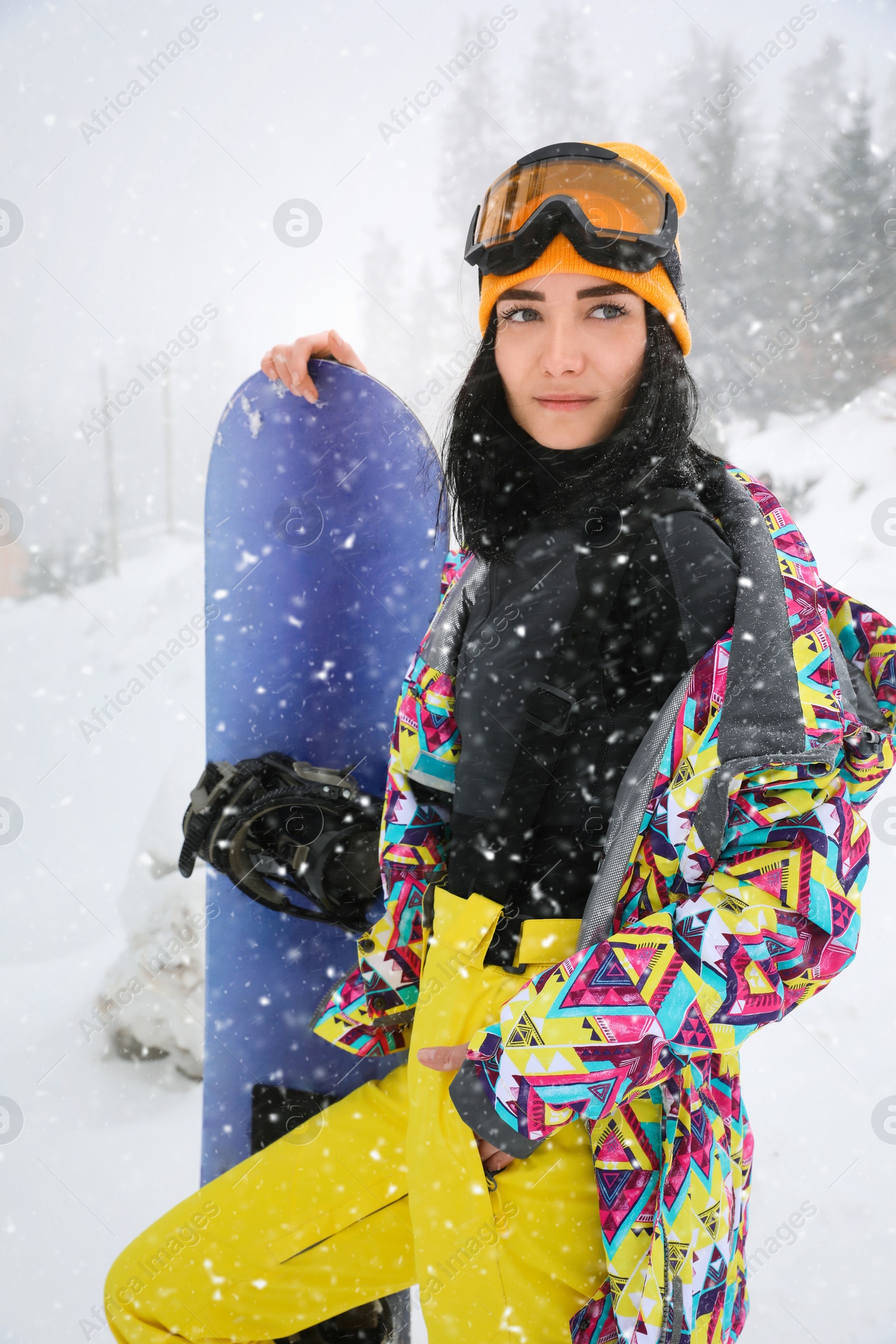 Photo of Young woman with snowboard wearing winter sport clothes outdoors