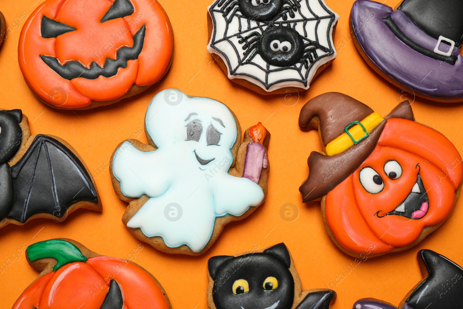 Photo of Different decorated gingerbread cookies on orange background, flat lay. Halloween celebration