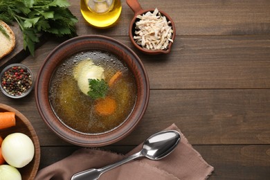 Photo of Delicious chicken bouillon and ingredients on wooden table, flat lay. Space for text