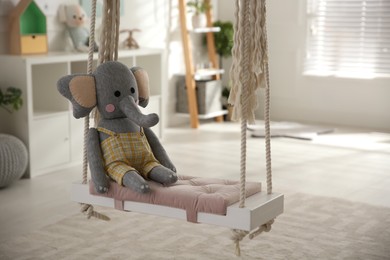 Photo of Beautiful swing with toy elephant in room. Stylish interior design