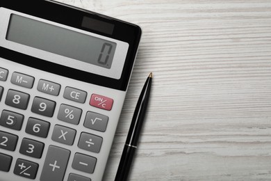 Photo of Calculator and pen on white wooden table, top view. Space for text