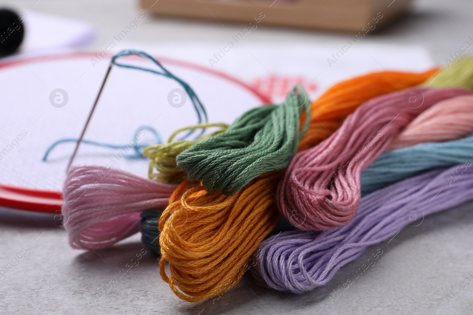 Photo of Different threads and embroidery hoop on light grey table