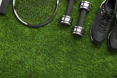 Photo of Different sports equipment on green grass, flat lay. Space for text