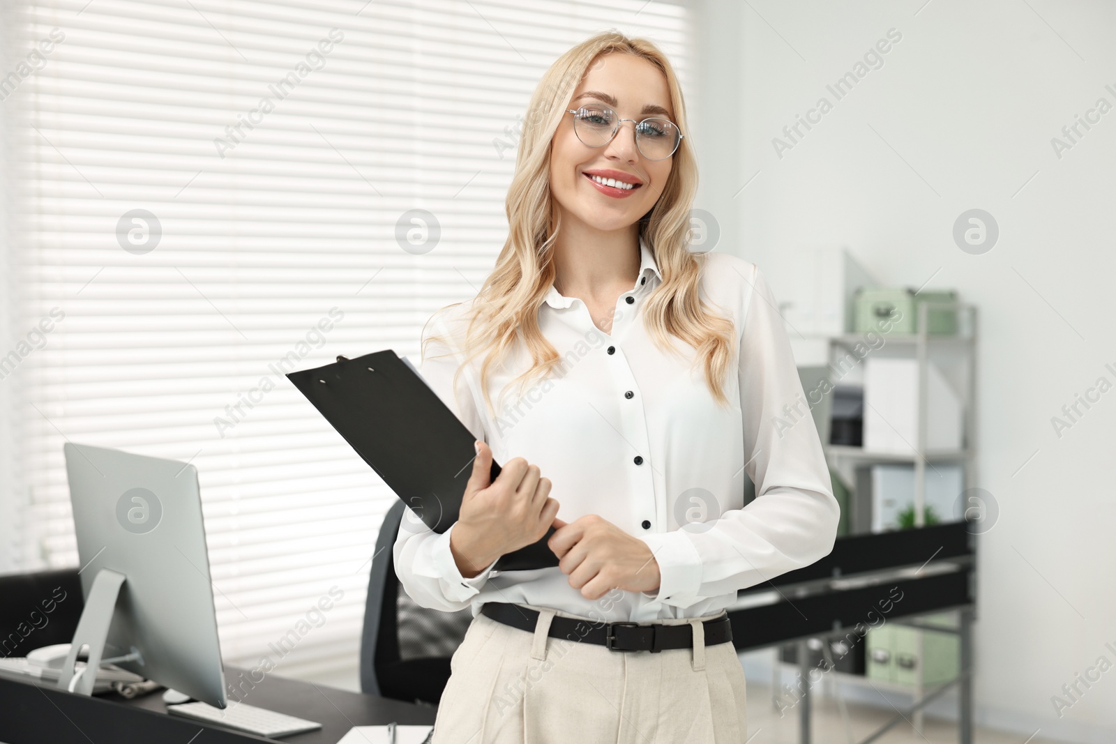 Photo of Happy secretary with glasses and clipboard in office