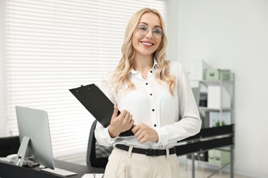 Happy secretary with glasses and clipboard in office