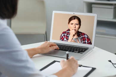 Hotline service. Doctor consulting patient online via laptop indoors