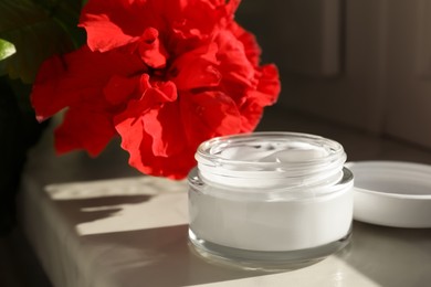 Photo of Jarface cream and flower on white table indoors
