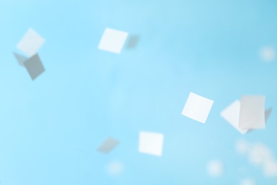 Photo of White confetti falling down on light blue background
