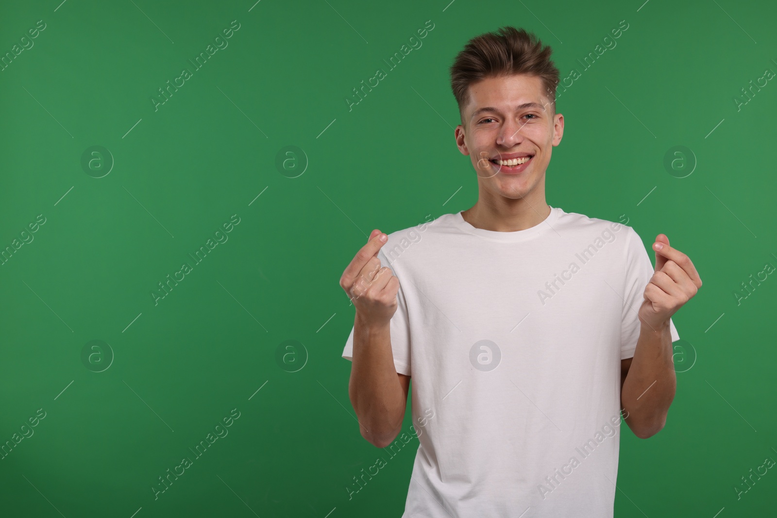 Photo of Happy man showing money gesture on green background. Space for text