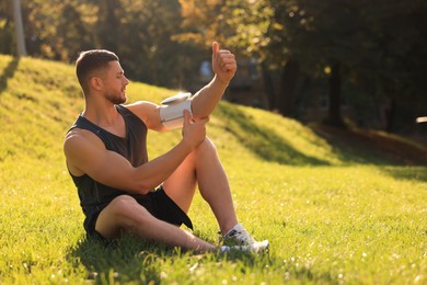 Attractive man checking blood pressure with modern monitor after training in park. Space for text
