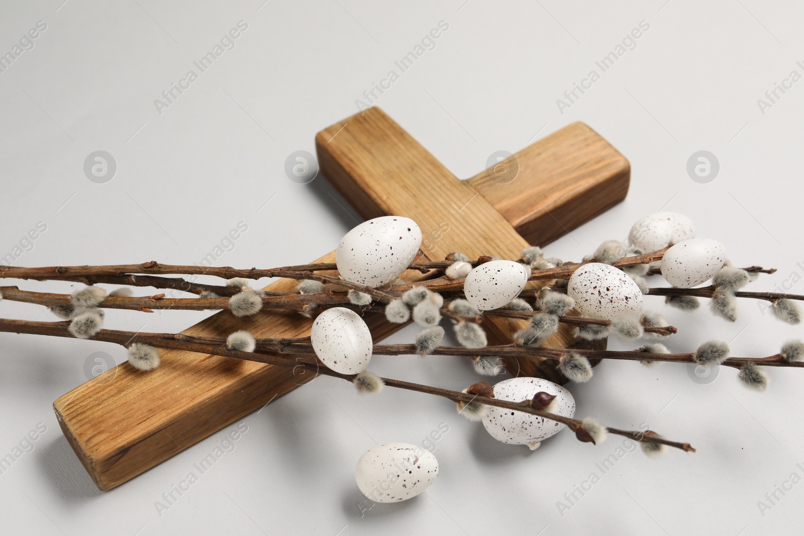 Photo of Wooden cross, painted Easter eggs and willow branches on light grey background