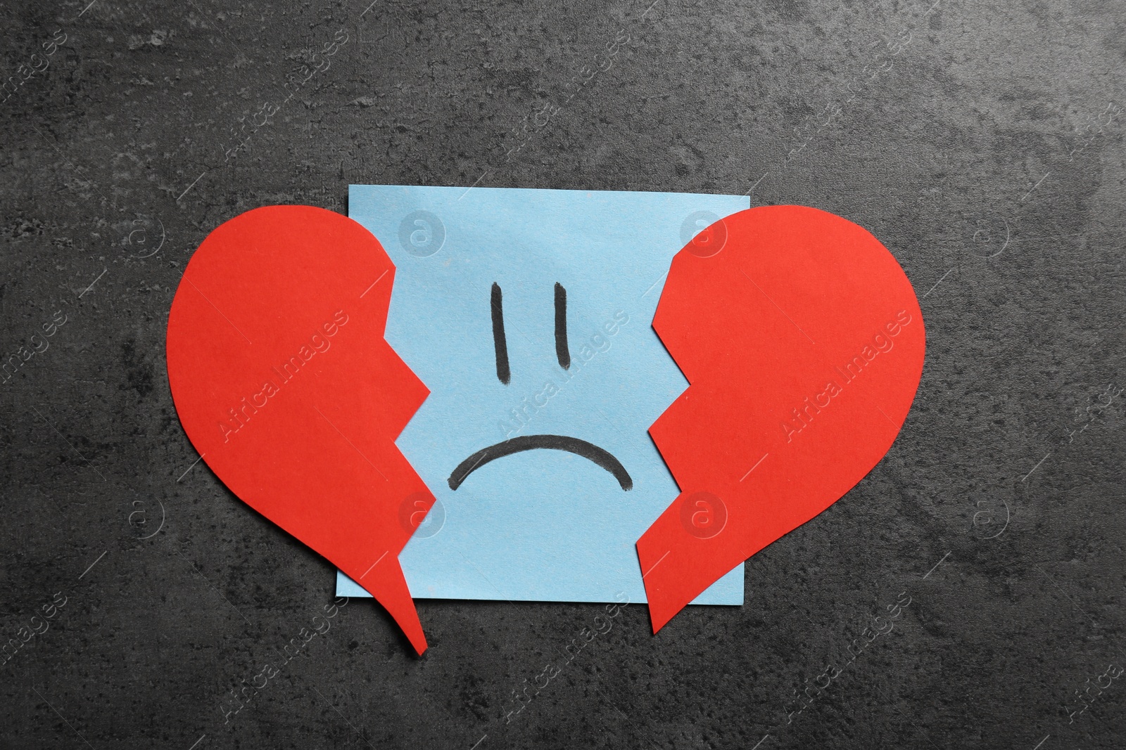 Photo of Sticker with sad face and broken heart on grey background, flat lay