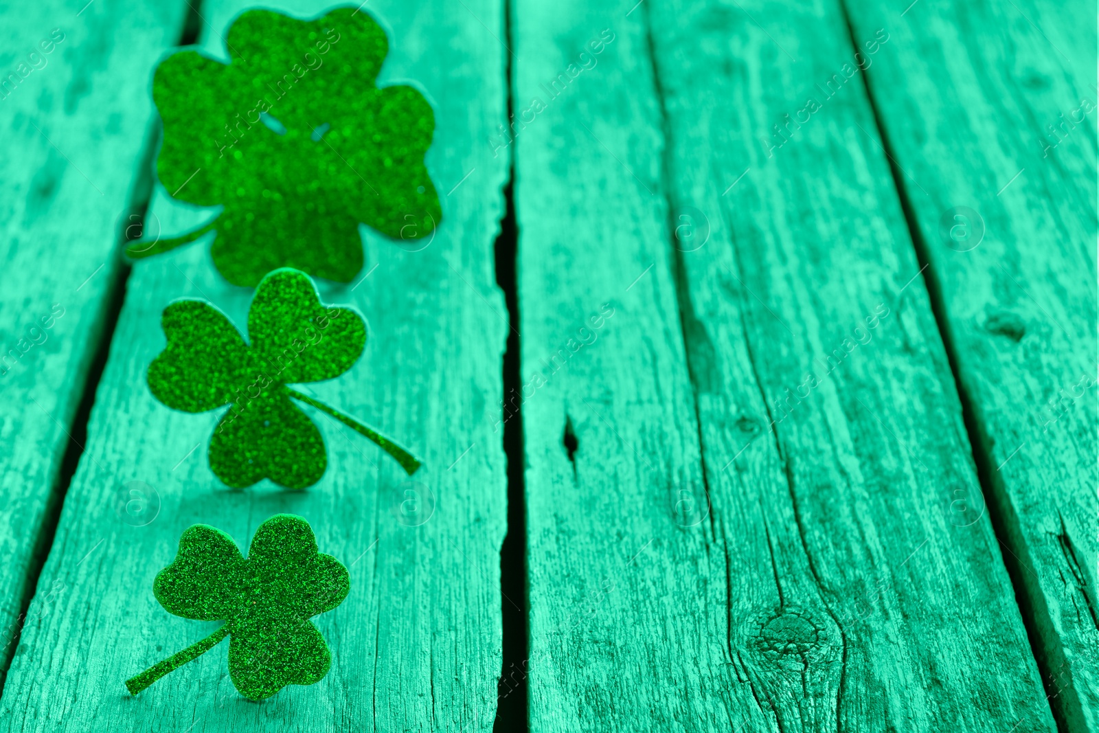 Image of St. Patrick's day. Decorative clover leaves on green wooden background, space for text