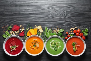 Various soups, ingredients and space for text on wooden background, flat lay. Healthy food