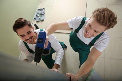 Photo of Young workers installing drywall indoors, above view. Home repair service