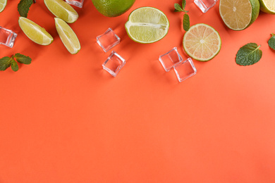 Photo of Lemonade layout with juicy lime slices, mint and ice cubes on coral background, top view. Space for text