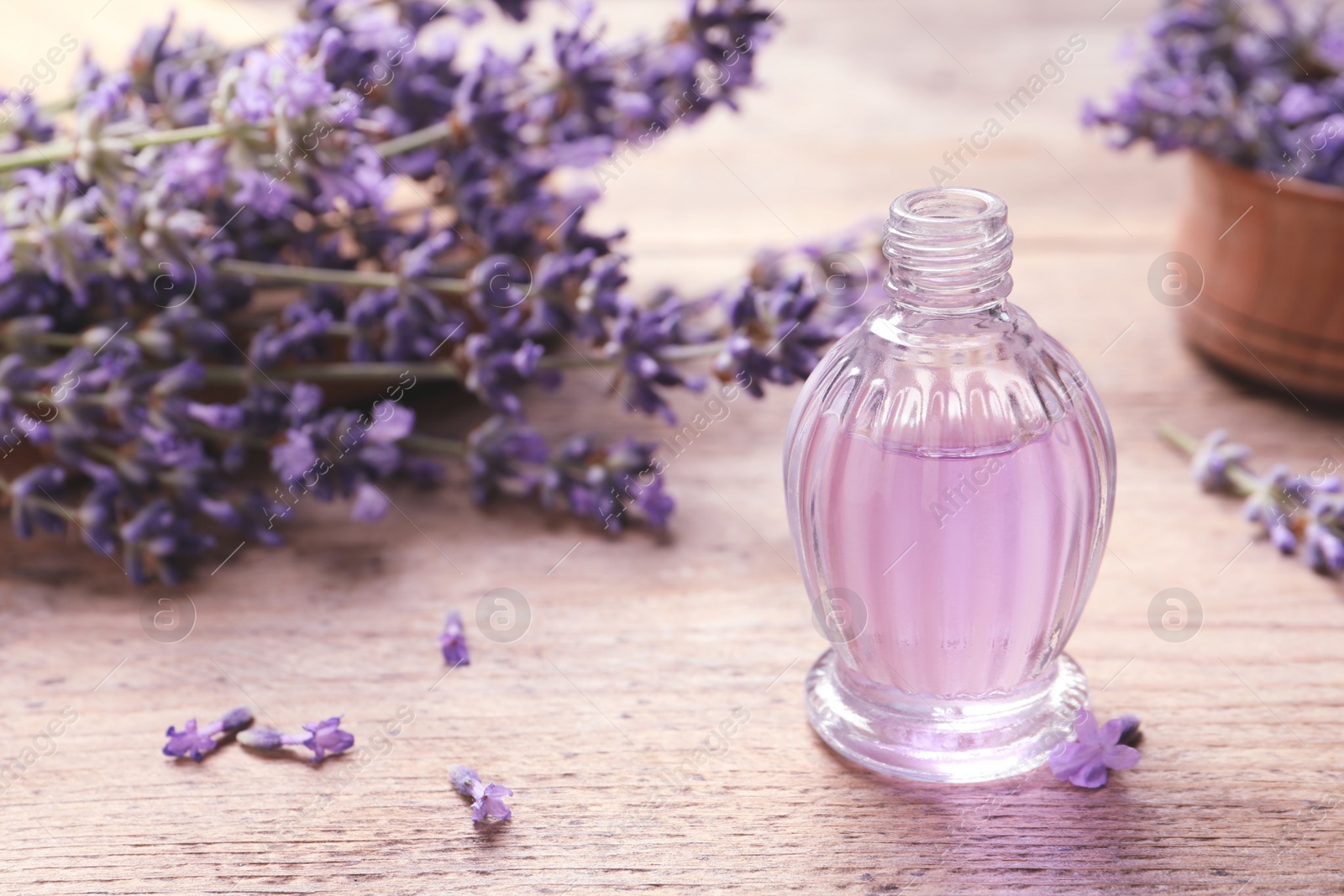 Photo of Glass bottle of natural cosmetic oil and lavender flowers on wooden table, space for text